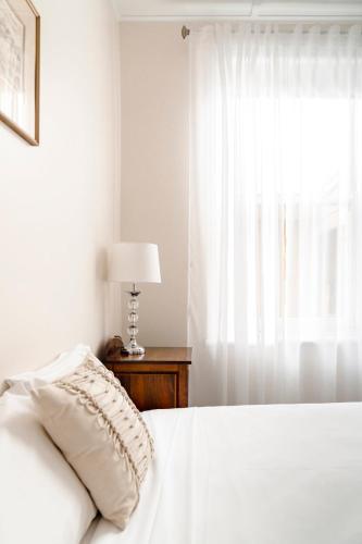 a white bed with a pillow and a window at Seaview House in Queenscliff