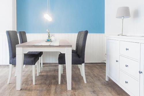 a dining room table with black chairs and a blue wall at Amoy - Werftstraße 2 in Heiligenhafen