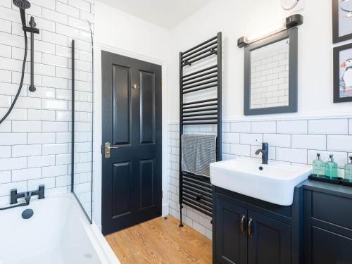 een badkamer met een wastafel, een bad en een spiegel bij Shorefront Apartment in Anstruther