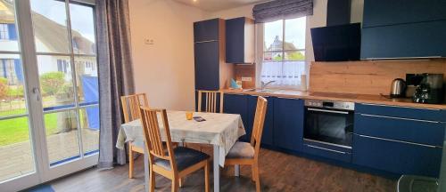 a kitchen with a table and chairs and a kitchen with blue cabinets at Reethaus "Melsa" in Zierow
