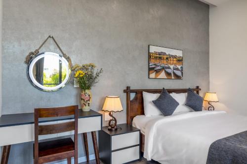 ein Schlafzimmer mit einem Bett, einem Spiegel und einem Stuhl in der Unterkunft Anchie Retreat Villa Hội An in An Bàn (2)