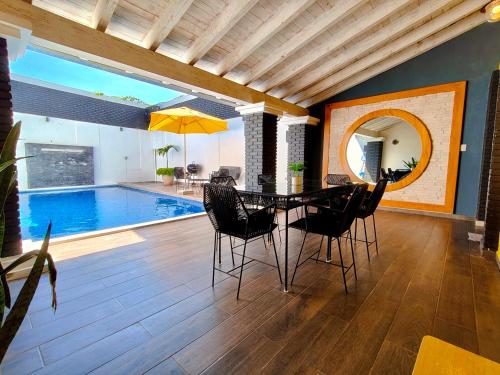 una sala da pranzo con tavolo, sedie e piscina di Casa Rinconcito Del Sol Alberca Climatizada a Tonatico