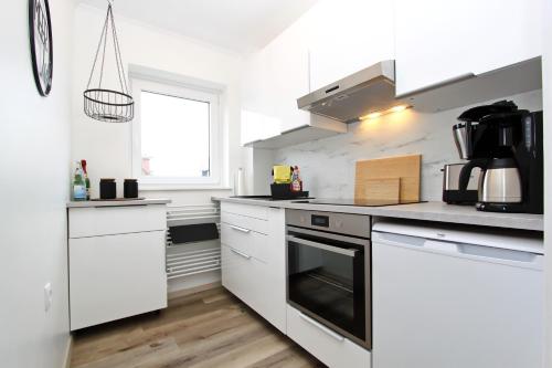 a kitchen with white appliances and a window at Meer-Liebe in Hörnum