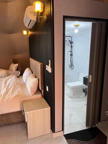 a bedroom with a bed and a bathroom with a toilet at Madonna Rum camp bubbles & Jeep tours in Wadi Rum