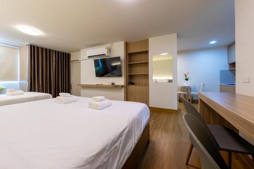 a hotel room with two beds and a desk at Chorbnorn Hotel in Lampang