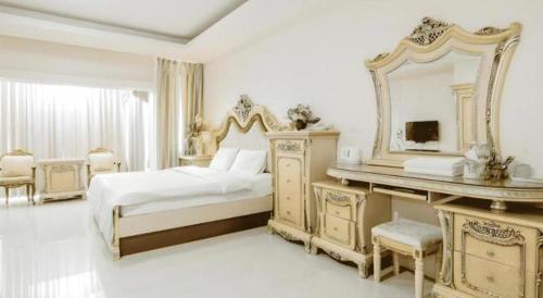 een witte slaapkamer met een bed en een spiegel bij Crystal Place Buayai in Bua Yai