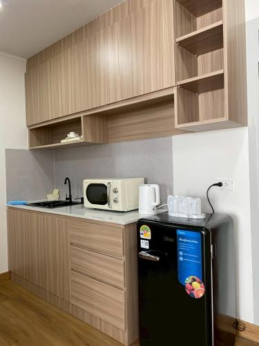 a kitchen with a black refrigerator and a microwave at Chorbnorn Hotel in Lampang