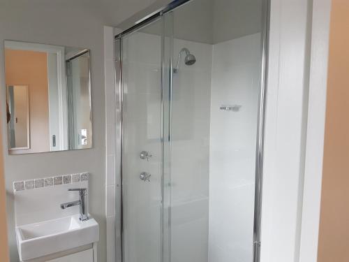 a shower with a glass door next to a sink at Mandurah Foreshore Motel in Mandurah