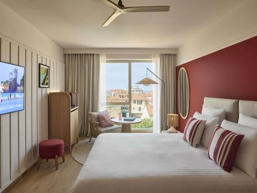 een hotelkamer met een groot bed en een raam bij Le Talaia Hôtel & Spa Biarritz - MGallery Collection in Biarritz