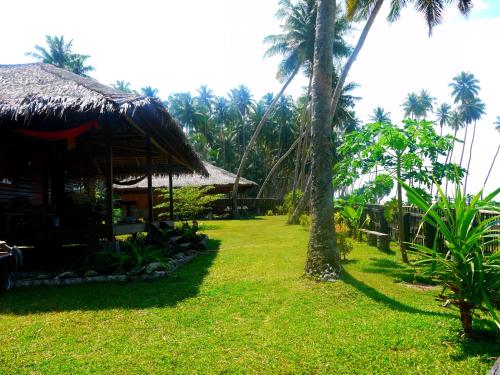 a resort with palm trees and a grass yard at Kita Surf Resort in Lasikin