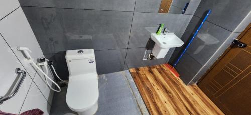 a bathroom with a white toilet and a sink at Karmalhills Homestay in Tindummal