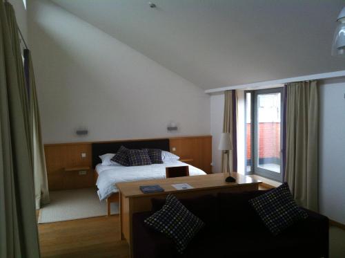 a hotel room with a bed and a desk and a table at Irish College Leuven in Leuven