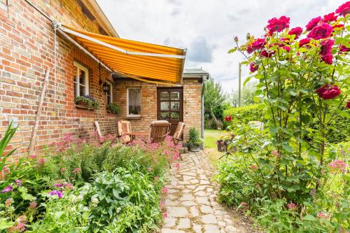 a garden with flowers and a brick house at Ferienwohnung Ina Meta in Reppenhagen