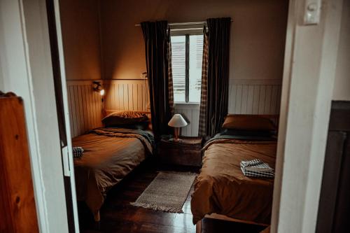 a small bedroom with two beds and a window at Two Brothers' Cabin in Deeside