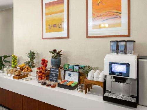 um balcão de pequeno-almoço com máquina de café e frutas em The Sydney Boulevard Hotel em Sidney
