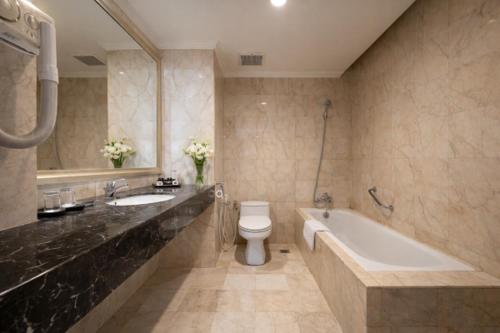 un bagno con vasca, WC e lavandino di The Mirah Hotel Bogor a Bogor