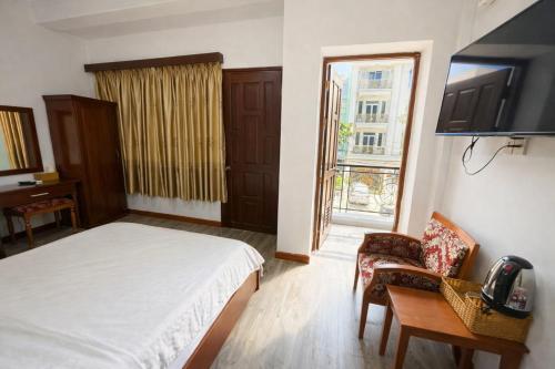 een slaapkamer met een bed, een televisie en een stoel bij Tâm Tín Hotel Hồ Chí Minh in Ho Chi Minh-stad