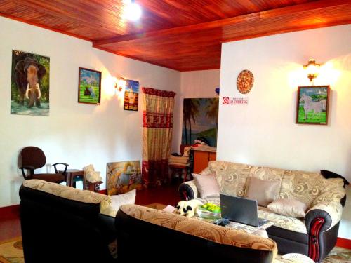 a living room with two couches and a laptop at Eeshani Guest Inn in Ella