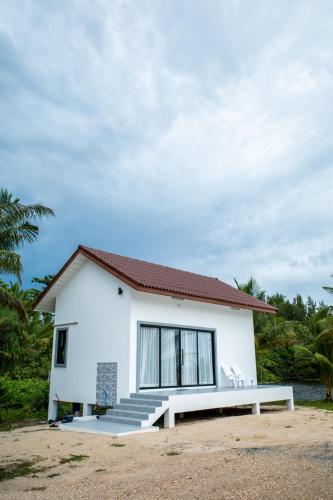 a white house with a bench in front of it at The Rock Coco Villa 2 in Ban Sai Mat