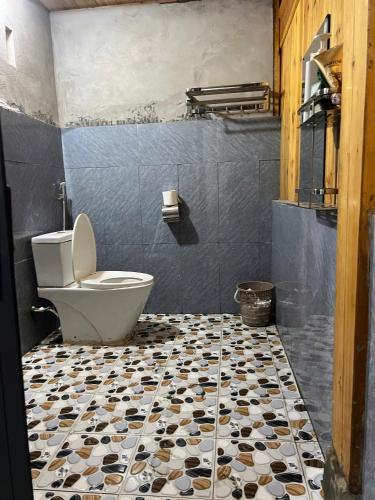 a bathroom with a toilet and a tiled floor at Local Homestay in Sapa
