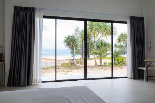 a bedroom with a large window with a view of the beach at The Rock Coco Villa 2 in Ban Sai Mat