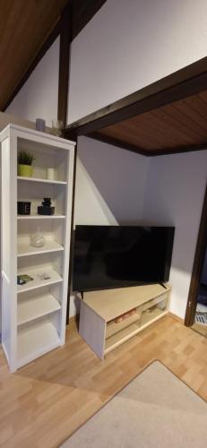 a white book shelf with a tv in a room at Quartier132 - Das All-Inklusive Ferienhaus in Öfingen