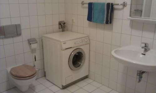ein Badezimmer mit einer Waschmaschine und einem Waschbecken in der Unterkunft Appartements Am Theater in Weimar