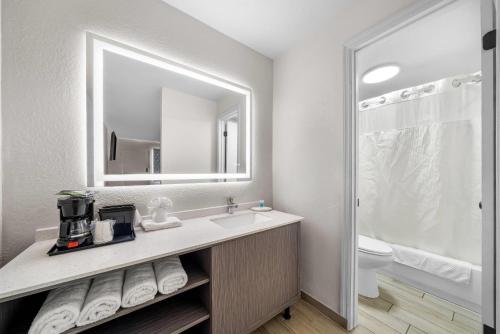 een badkamer met een wastafel en een spiegel en een toilet bij Rodeway Inn Lake Wales - Winter Haven in Lake Wales