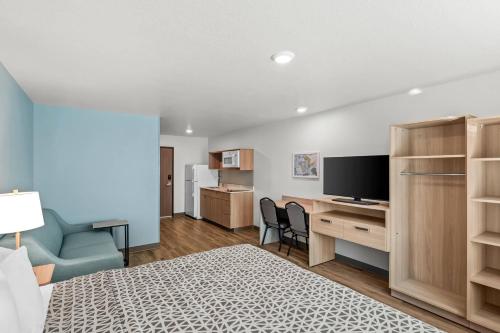 a room with a bed and a desk with a television at WoodSpring Suites Palm Springs - West Palm Beach in Palm Springs