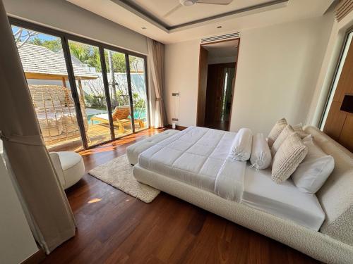 a bedroom with a large bed and a large window at Anchan Flora Luxury 2BR Pool Villa in Thalang