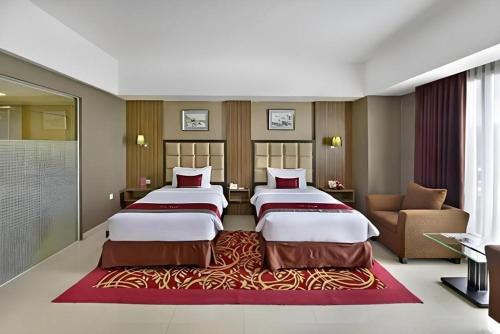 ein Hotelzimmer mit zwei Betten und einer Couch in der Unterkunft Travello Hotel Bandung in Bandung