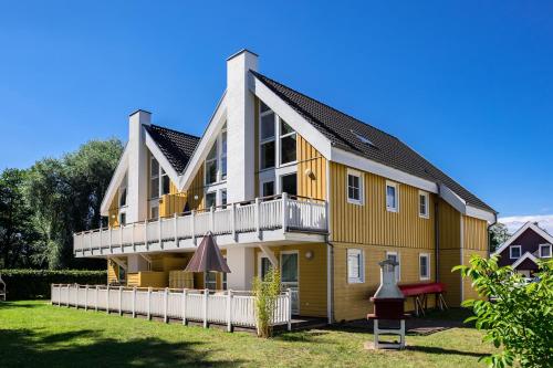 a large yellow house with a white fence at Marinapark Scharmützelsee in Wendisch Rietz
