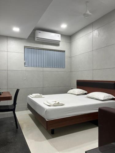 a bedroom with a bed and a desk and a bed sidx sidx sidx at Vijey Hotels in Tiruchirappalli