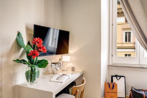 a vase of red flowers on a table with a tv at The Club Navona in Rome