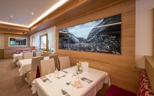 a restaurant with white tables and chairs and a large window at Hotel Neue Post in Hippach