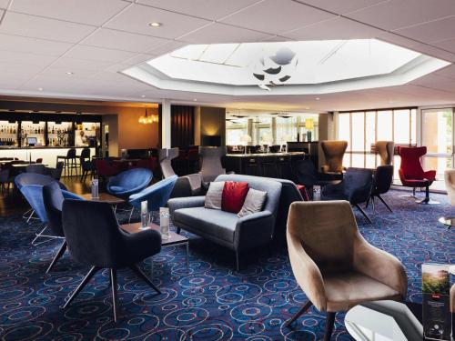 een lobby met stoelen en tafels en een bar bij Novotel Nottingham Derby in Long Eaton