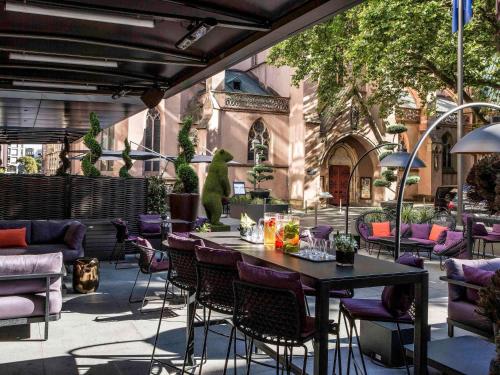 een terras met een tafel en stoelen en een gebouw bij Sofitel Strasbourg Grande Ile in Straatsburg