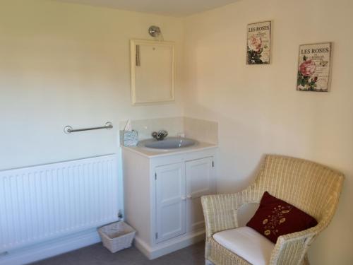 a bathroom with a sink and a chair and a mirror at Leadenham Cottage in Oakham