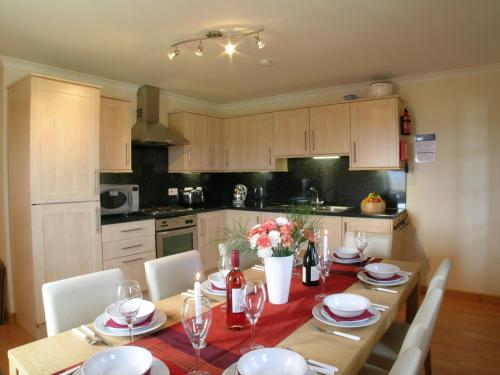 cocina con mesa de madera con sillas y comedor en Waterfall View, en Milovaig