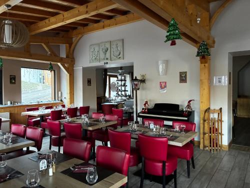 een restaurant met rode stoelen en tafels en een piano bij Hôtel du Centre - Restaurant Lelex'ir in Lélex