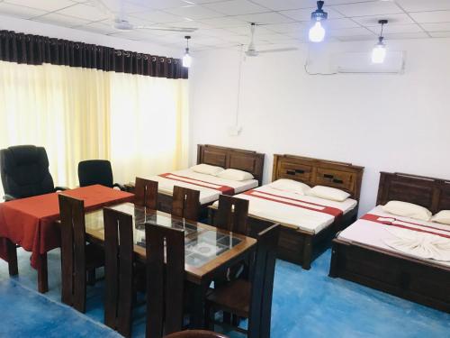 una camera con quattro letti e un tavolo con sedie di Elliot Nature Resort a Galle