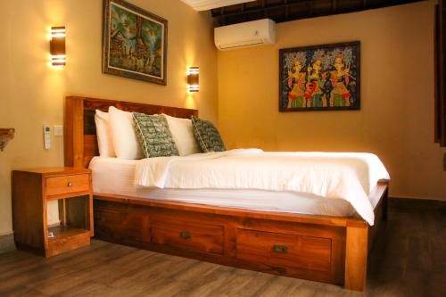 een slaapkamer met een groot bed met witte lakens bij Ananda House in Ubud