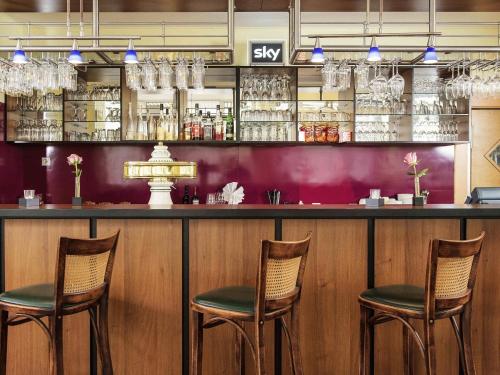 un bar con tre sedie di fronte di ibis Paderborn City a Paderborn