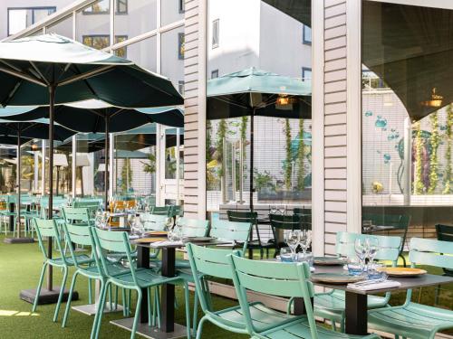een restaurant met tafels, stoelen en parasols bij ibis Lyon Gerland Musée des Confluences in Lyon