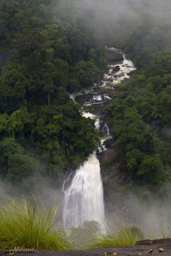 a waterfall in the middle of a river with trees at Skyfall Villa in Chillithodu