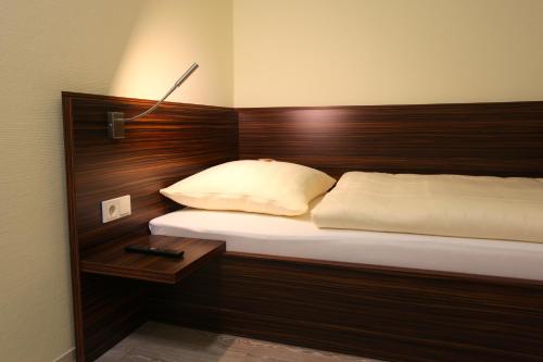 a bedroom with a bed with a wooden head board at Hotel Alter Zoll in Kleinblittersdorf