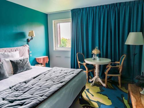 een slaapkamer met een bed en een tafel met stoelen bij Hotel Mercure Parc du Coudray - Barbizon in Le Coudray-Montceaux