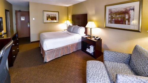 um quarto de hotel com uma cama e duas cadeiras em Holiday Inn Express St. Jean Sur Richelieu, an IHG Hotel em Saint-Jean-sur-Richelieu