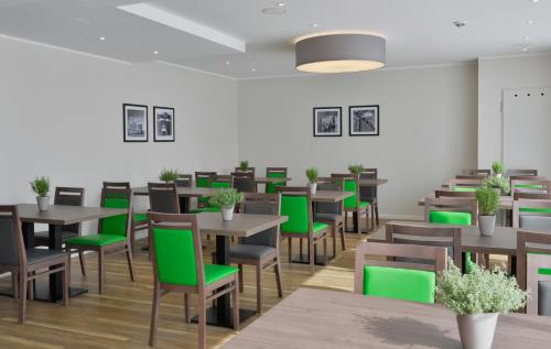 a dining room with tables and green chairs at Appartello Smarttime living Hamburg in Hamburg
