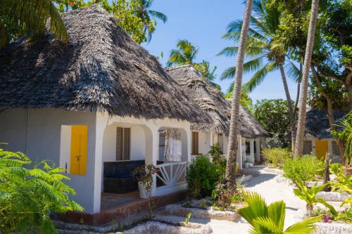 a cottage on the beach with palm trees at ZAN Uhuru Jambiani Beach in Bwejuu